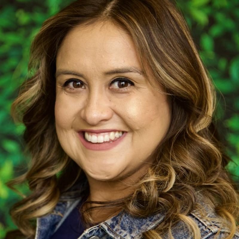 Photo of Karina Garcia wearing a denim jacket with green background.
